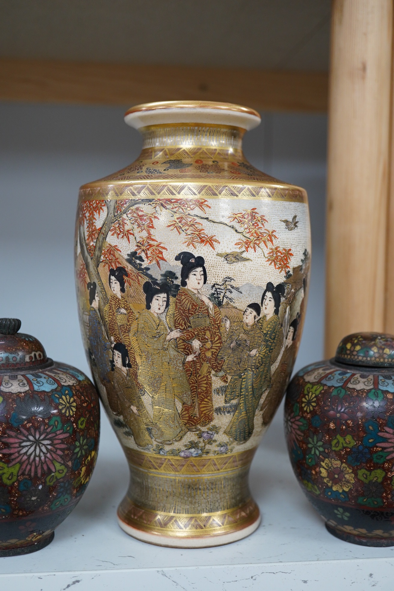 A pair of Japanese cloisonné enamel jars and covers, a Japanese bronze and gold overlaid small vase and a Satsuma pottery vase, tallest 22cm high (4). Condition - finial loose and one missing on cloisonné jars and covers